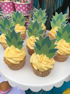 cupcakes with yellow frosting and pineapple decorations on a cake platter