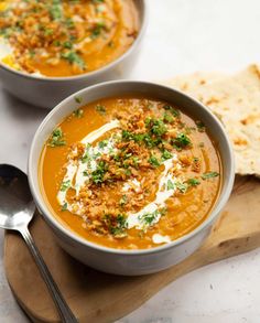 two bowls of soup with bread on the side