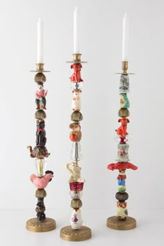 three tall candlesticks with glass beads and figurines on each candle holder