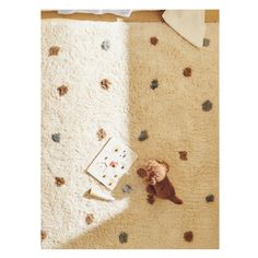 a teddy bear is laying on the floor next to a rug with small stars and dots