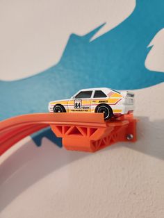 a toy car is on top of an orange track that's attached to a wall