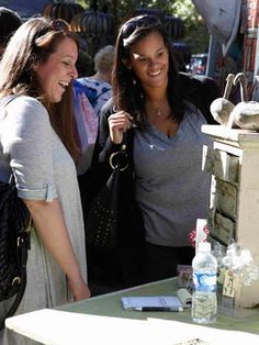 three women standing next to each other in front of a table with items on it