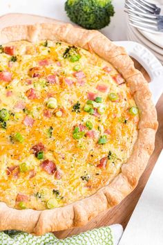 a quiche with ham, cheese and broccoli in a pie pan on a table