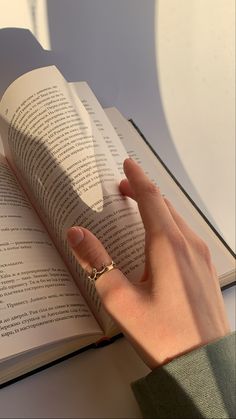 a person is reading a book with their hand on top of the book's cover