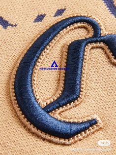 a close up of a blue and beige sweater with the letter q in it's center