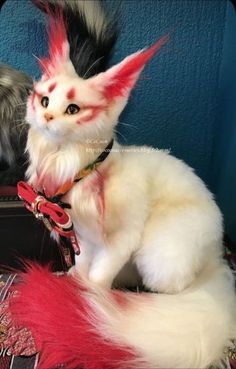 a white and black cat with red hair sitting on top of a luggage bag in front of a blue wall