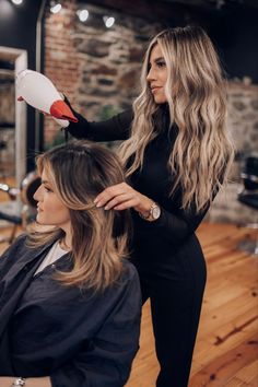 a woman is getting her hair done by another woman in a salon at the same time