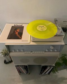 a yellow record player sitting on top of a white shelf next to a vinyl album