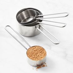 a measuring cup filled with powder next to metal utensils on a marble surface