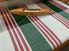 a close up of a weaving machine with red and green stripes on the table cloth