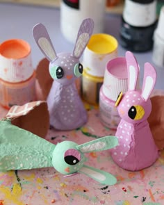 paper mache rabbits sitting on top of a table next to paint bottles and scissors