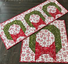 two quilted christmas placemats sitting on top of a wooden floor