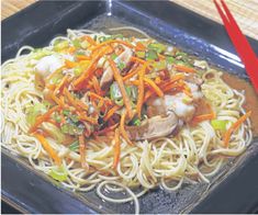 a black plate topped with noodles and vegetables