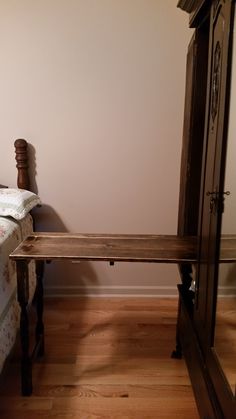 a wooden bench sitting next to a bed on top of a hard wood floored floor