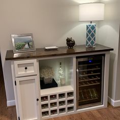 a wine cabinet with many bottles in it and a lamp on the wall behind it