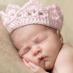 a newborn baby wearing a pink crochet crown sleeping on top of a blanket