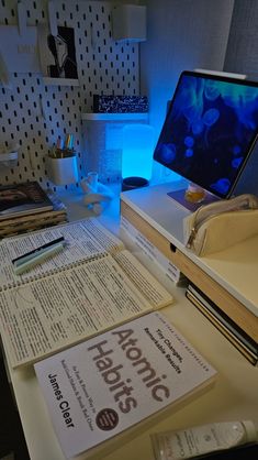 an office desk with books and a computer monitor on it's side, lit up by blue light