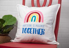 a white pillow that says anything is possible together on it next to a potted plant