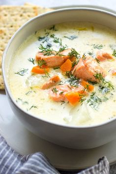 a white bowl filled with soup next to crackers