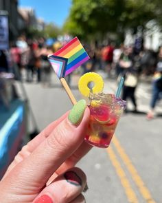 a person holding up a drink with a rainbow flag on the stick in their hand