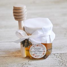 a jar filled with honey sitting on top of a wooden table next to a white ribbon