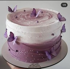 there is a cake with purple butterflies on the frosting and icing, it looks like something out of a fairy tale