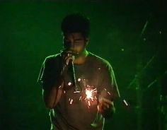 a man standing in front of a microphone on stage holding a sparkler up to his mouth