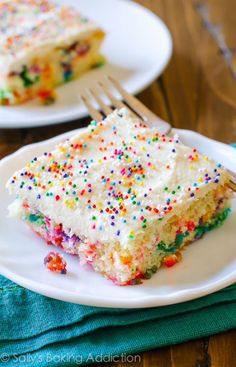 a slice of cake with sprinkles on a white plate next to a fork