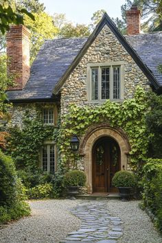 a stone house with ivy growing all over it's walls and door, surrounded by greenery