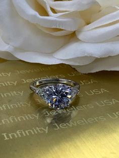 a white rose sitting on top of a table next to a diamond ring and wedding band