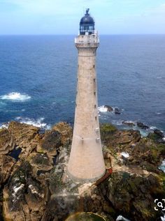 a light house sitting on top of a rocky cliff next to the ocean