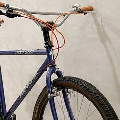 a blue bike with orange cables attached to it's handlebars against a white wall