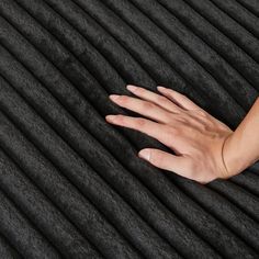 a woman's hand resting on top of an area rug that looks like pleated fabric