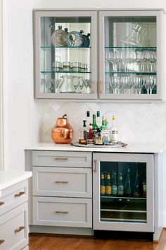 a kitchen with white cabinets and glass doors