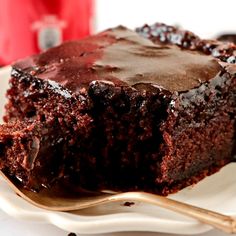 a piece of chocolate cake sitting on top of a white plate with a gold fork