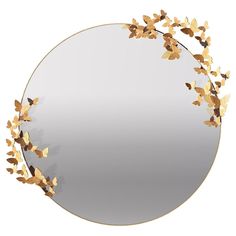 a round mirror with gold leaves on it