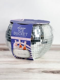 a silver disco ball sitting on top of a wooden table next to a package of ice buckets