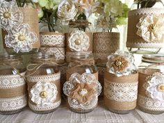 there are many jars that have flowers in them on the table with lace and burlocks