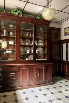 an old fashioned china cabinet with glass doors and drawers in the middle of a room