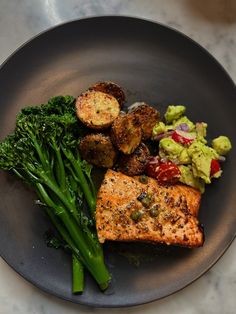 a black plate topped with meat and vegetables