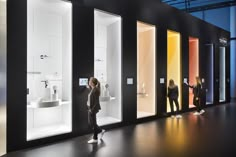 a woman is standing in front of several different colored glass cases that are on display