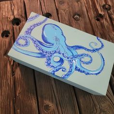 an octopus is painted on a white and blue box with wood planks in the background