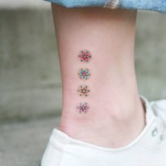 a woman's foot with four small flowers on the side of her leg and one flower in the middle