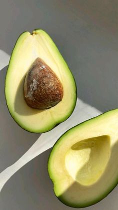 an avocado cut in half on a white surface