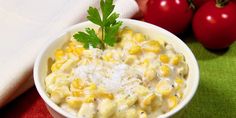 a white bowl filled with macaroni and cheese next to tomatoes on a table