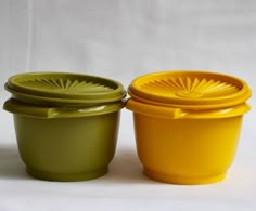 two yellow and green bowls sitting next to each other on a white tableclothed surface