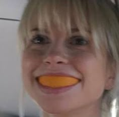 a woman with an orange slice in her mouth