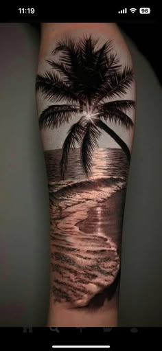 a man's arm with a palm tree on the beach and waves coming in