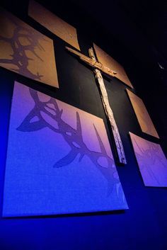 a cross is on the wall in front of some paintings that are blue and purple