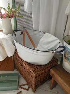 a large white tub sitting on top of a wooden table next to a basket filled with clothes